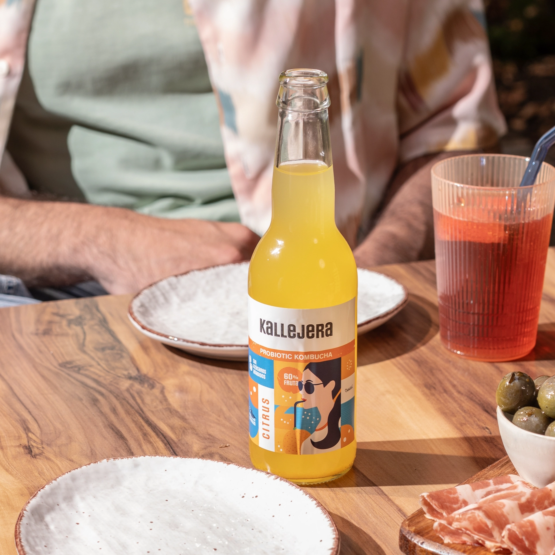 Botella de kombucha Kallejera Cítrica sobre una mesa de madera.