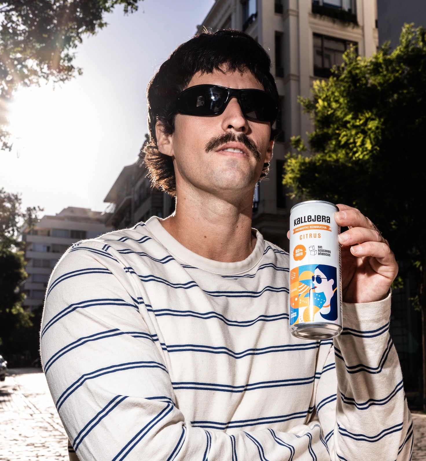 Hombre con gafas de sol sosteniendo una lata de kombucha.